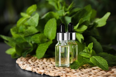 Photo of Bottles of essential oil and mint on grey table, closeup. Space for text