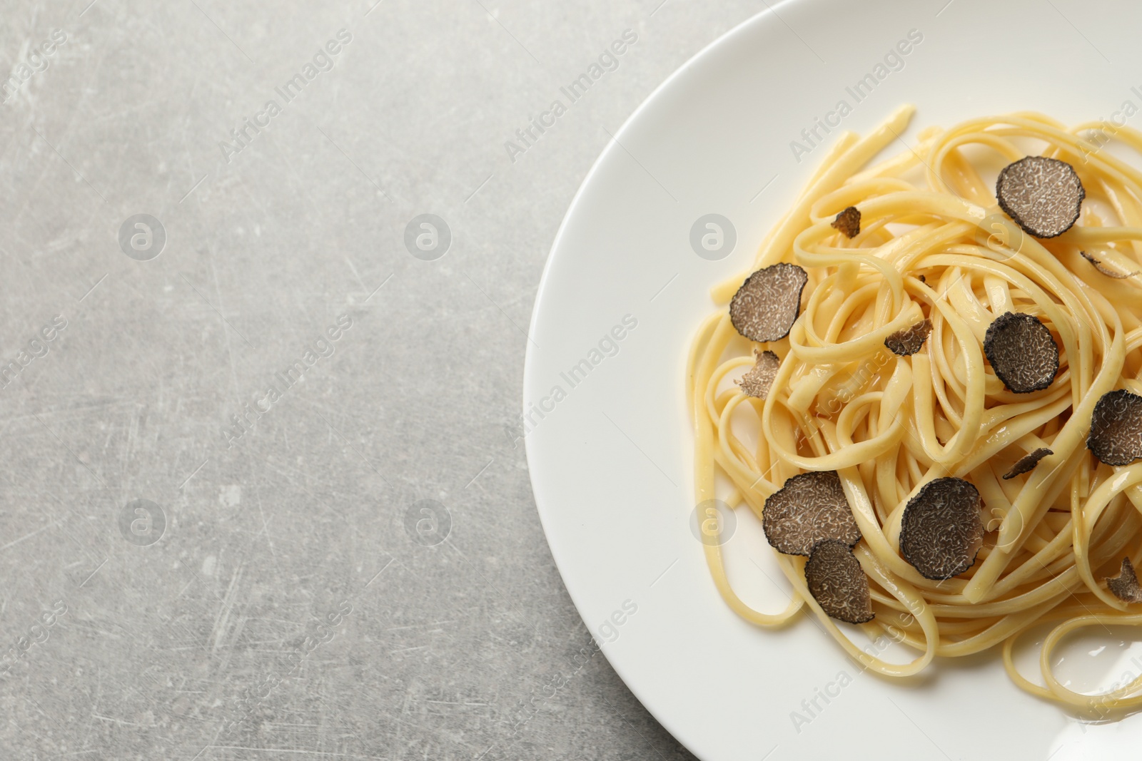 Photo of Tasty fettuccine with truffle on grey table, top view. Space for text