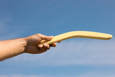 Photo of Man throwing boomerang against blue sky, closeup