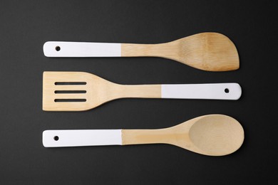 Photo of Wooden kitchen utensils on black background, flat lay
