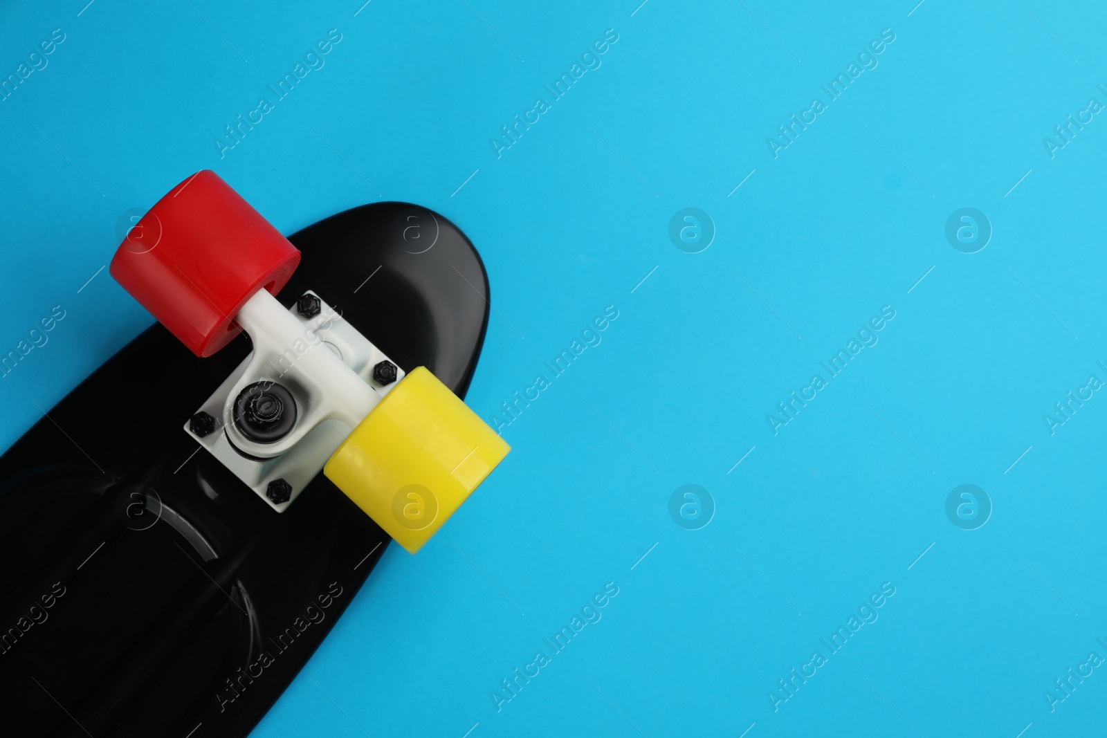 Photo of Skateboard on light blue background, top view. Space for text