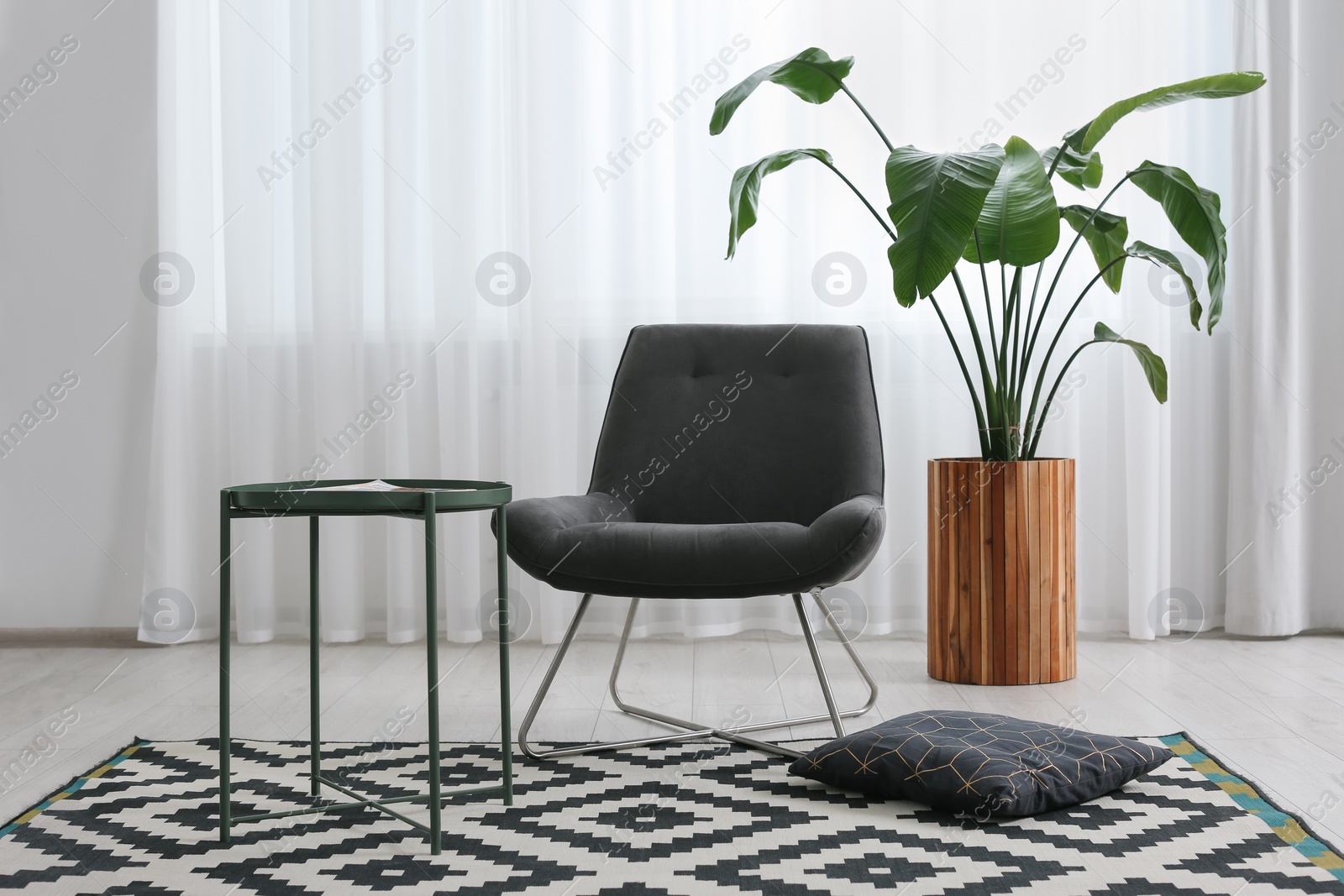 Photo of Stylish grey armchair and small coffee table in living room. Interior design