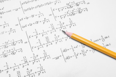 Sheet of paper with mathematical formulas and pencil, closeup
