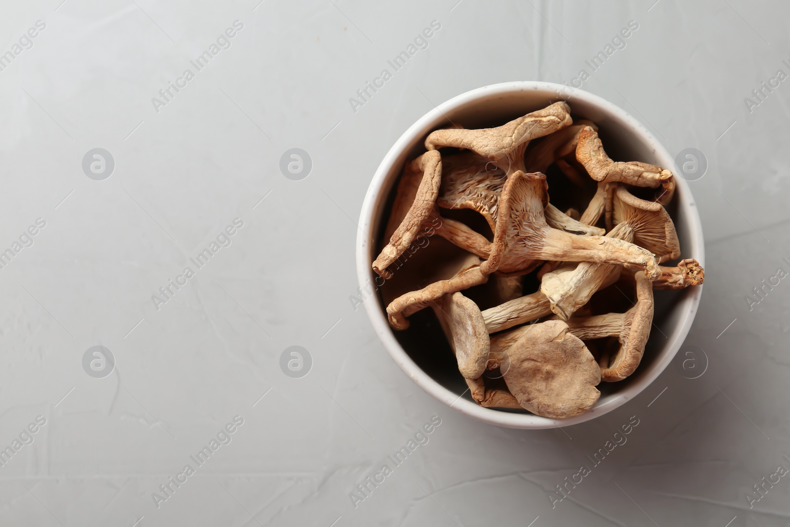 Photo of Bowl of dried mushrooms on color background, top view. Space for text