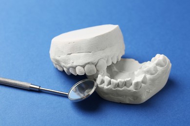 Photo of Dental model with gums and dentist mirror on blue background. Cast of teeth