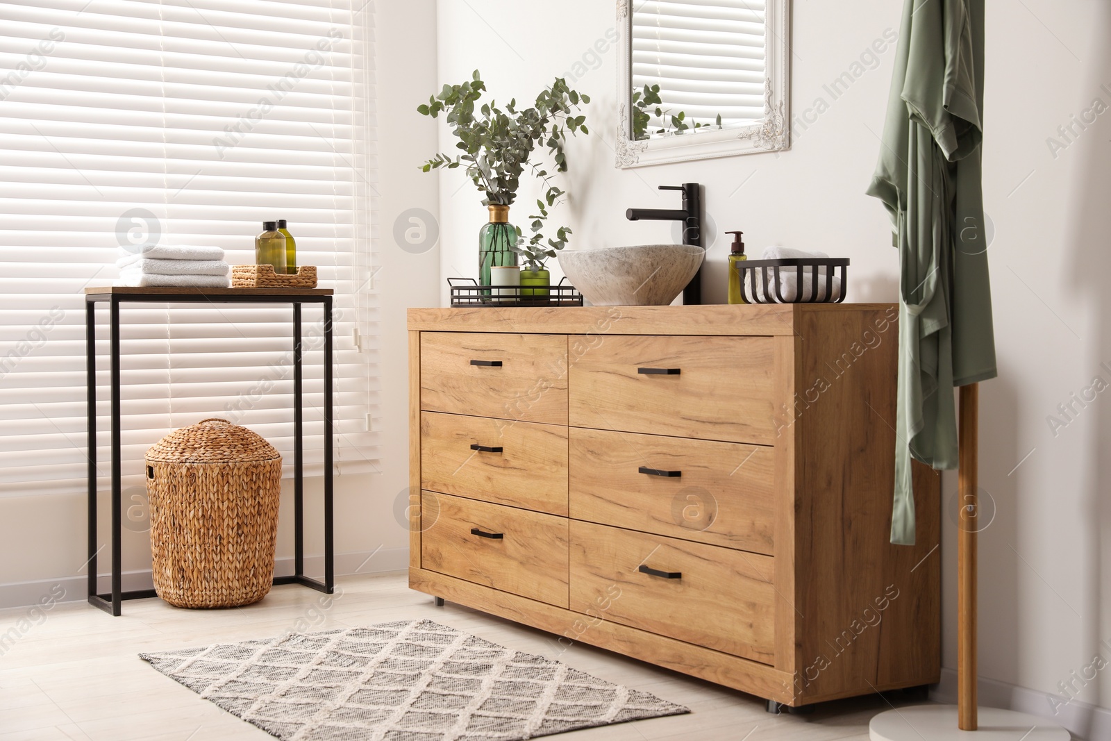 Photo of Modern bathroom interior with stylish mirror, eucalyptus branches, vessel sink and wooden vanity