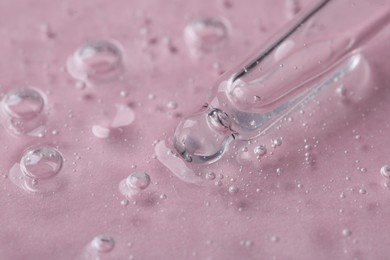 Pipette with cosmetic serum on pink background, closeup