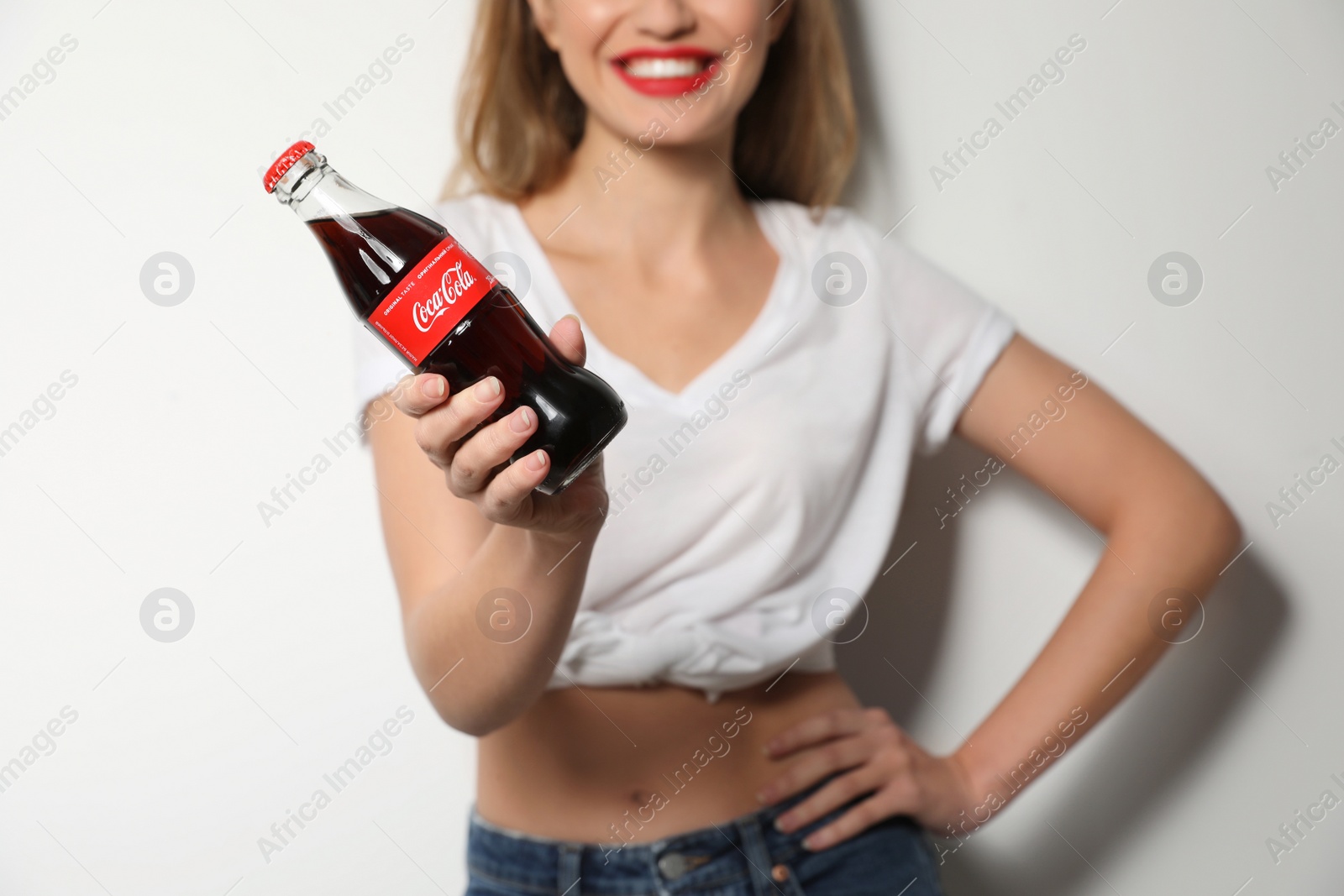 Photo of MYKOLAIV, UKRAINE - NOVEMBER 28, 2018: Young woman with bottle of Coca-Cola on white background, closeup