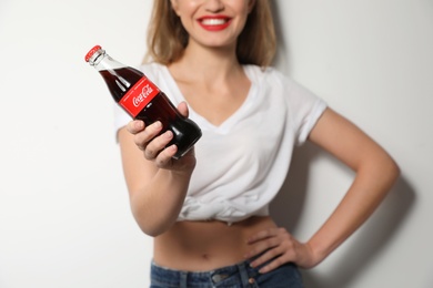 MYKOLAIV, UKRAINE - NOVEMBER 28, 2018: Young woman with bottle of Coca-Cola on white background, closeup