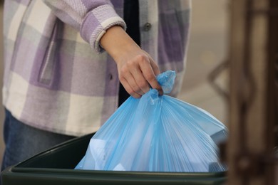 Photo of Woman putting garbage bag into recycling bin outdoors, closeup