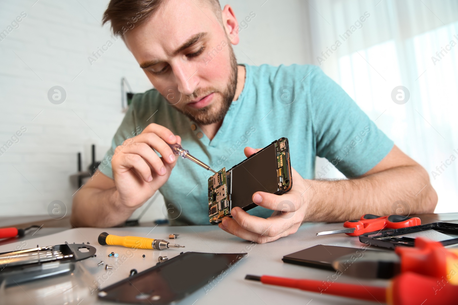 Photo of Technician repairing mobile phone at table in workshop, closeup