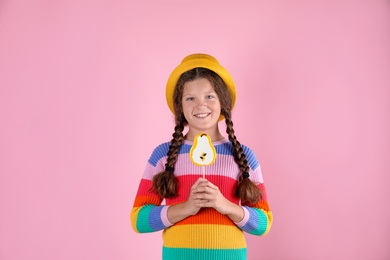 Little girl with candy on color background
