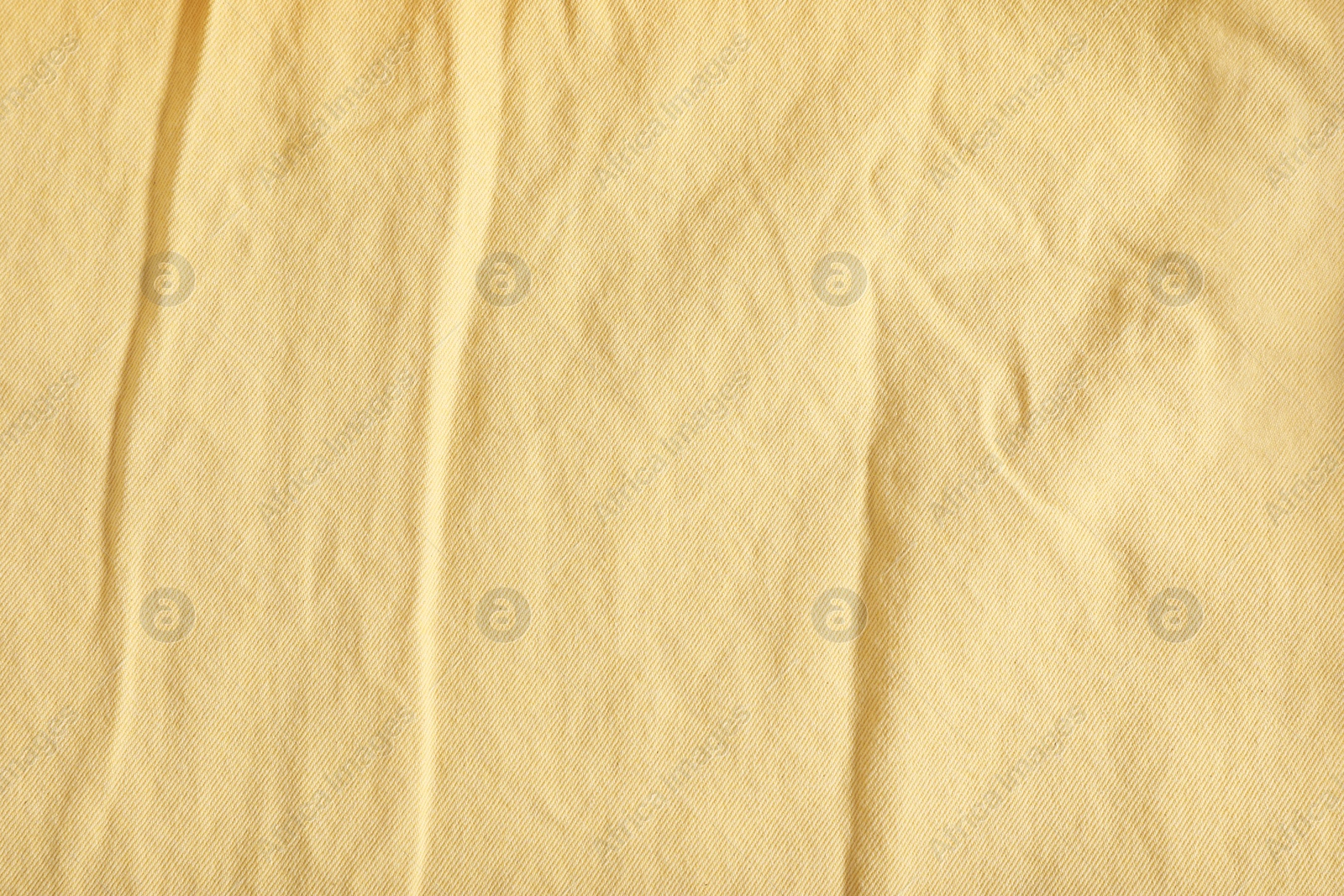 Photo of Crumpled pale yellow fabric as background, top view