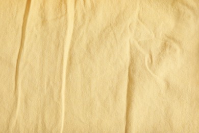 Crumpled pale yellow fabric as background, top view