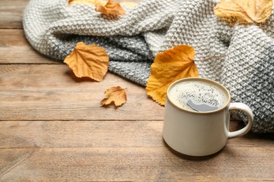 Composition with hot drink and warm plaid on wooden table