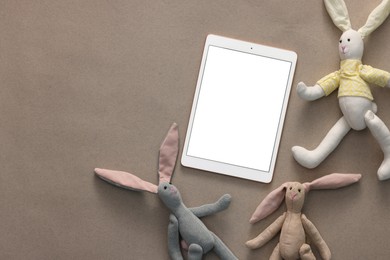 Photo of Modern tablet and kid's toys on light brown background, flat lay. Space for text