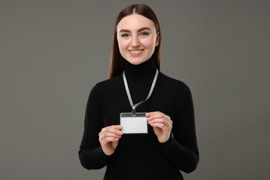 Happy woman with blank badge on grey background