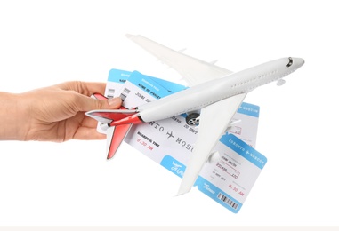 Woman holding toy airplane and tickets on white background, closeup