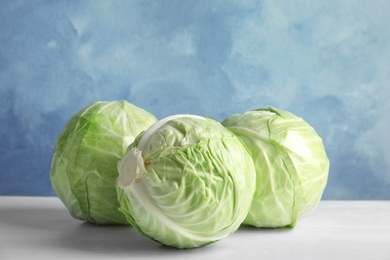 Photo of Whole cabbages on white table. Healthy food