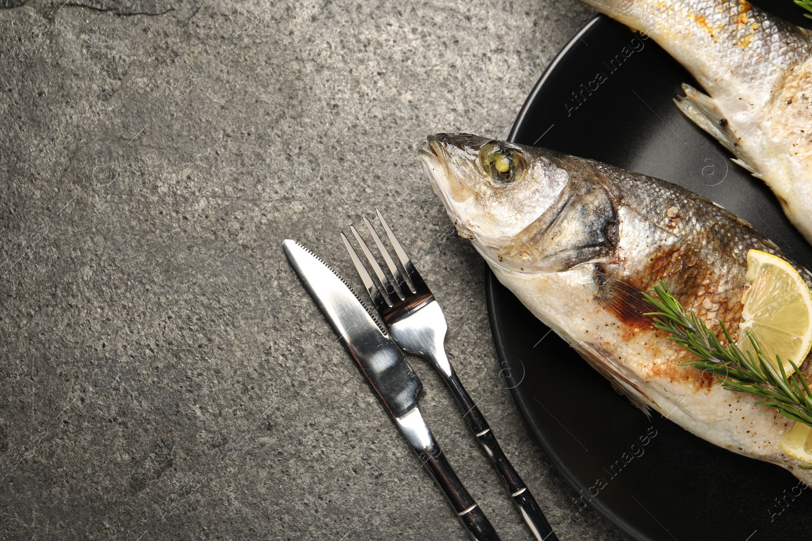 Photo of Delicious baked fish served on grey table, top view. Space for text