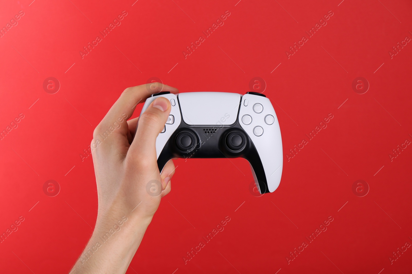 Photo of Man using wireless game controller on red background, closeup