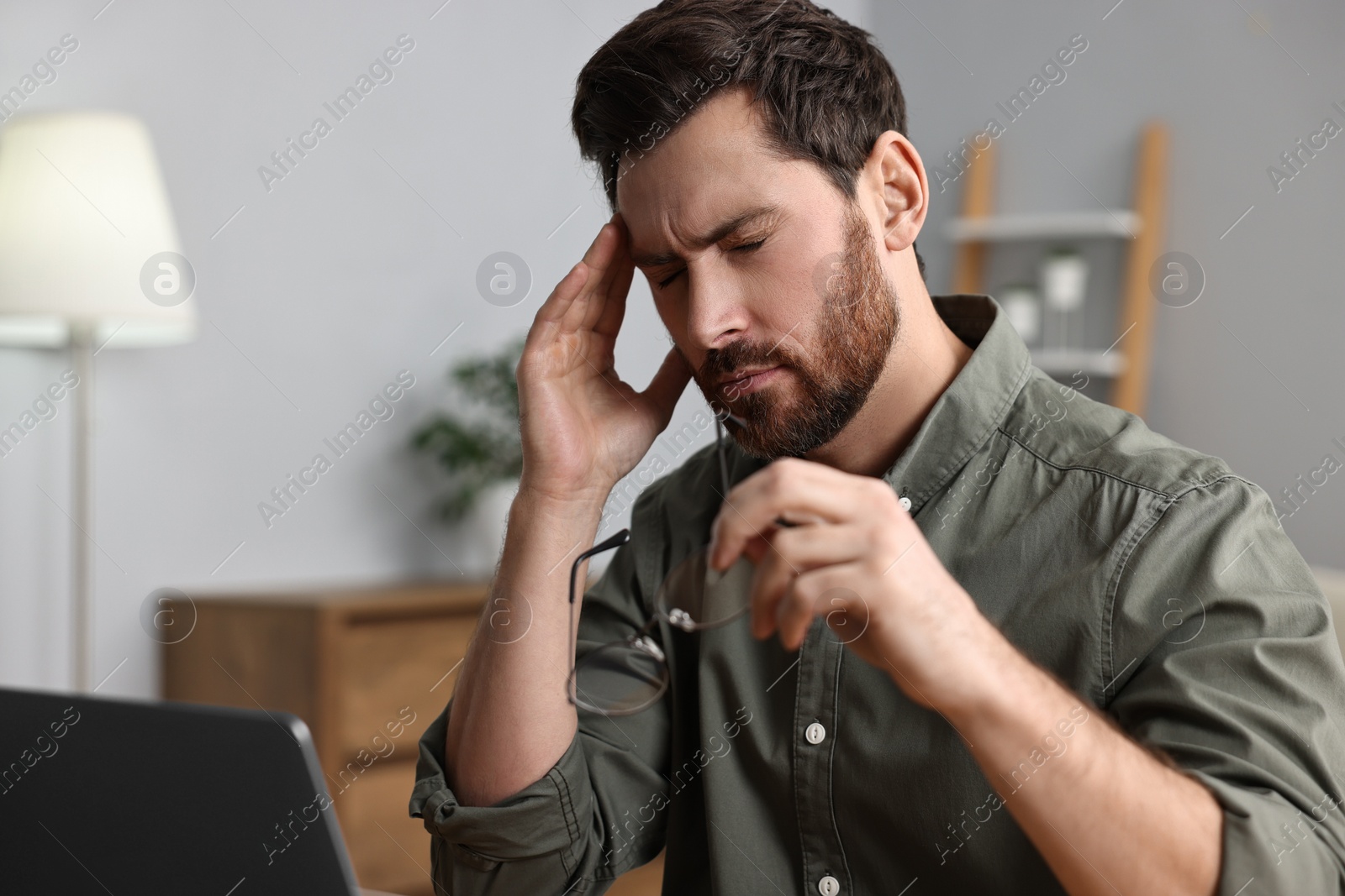 Photo of Tired man suffering from headache indoors. Space for text