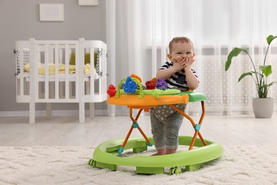 Photo of Cute baby making first steps with toy walker at home, space for text