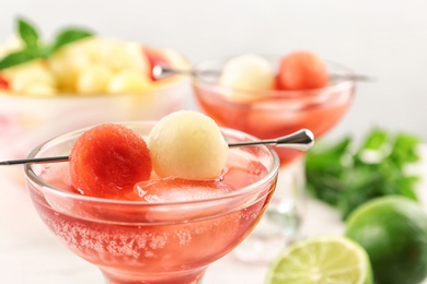 Photo of Glass of melon and watermelon ball cocktail on table, closeup