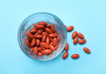 Photo of Glass with pills on turquoise background, flat lay. Anemia treatment