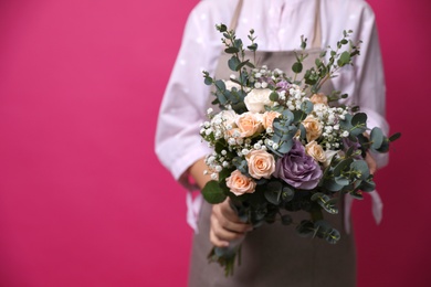 Photo of Florist holding beautiful wedding bouquet on pink background, closeup. Space for text