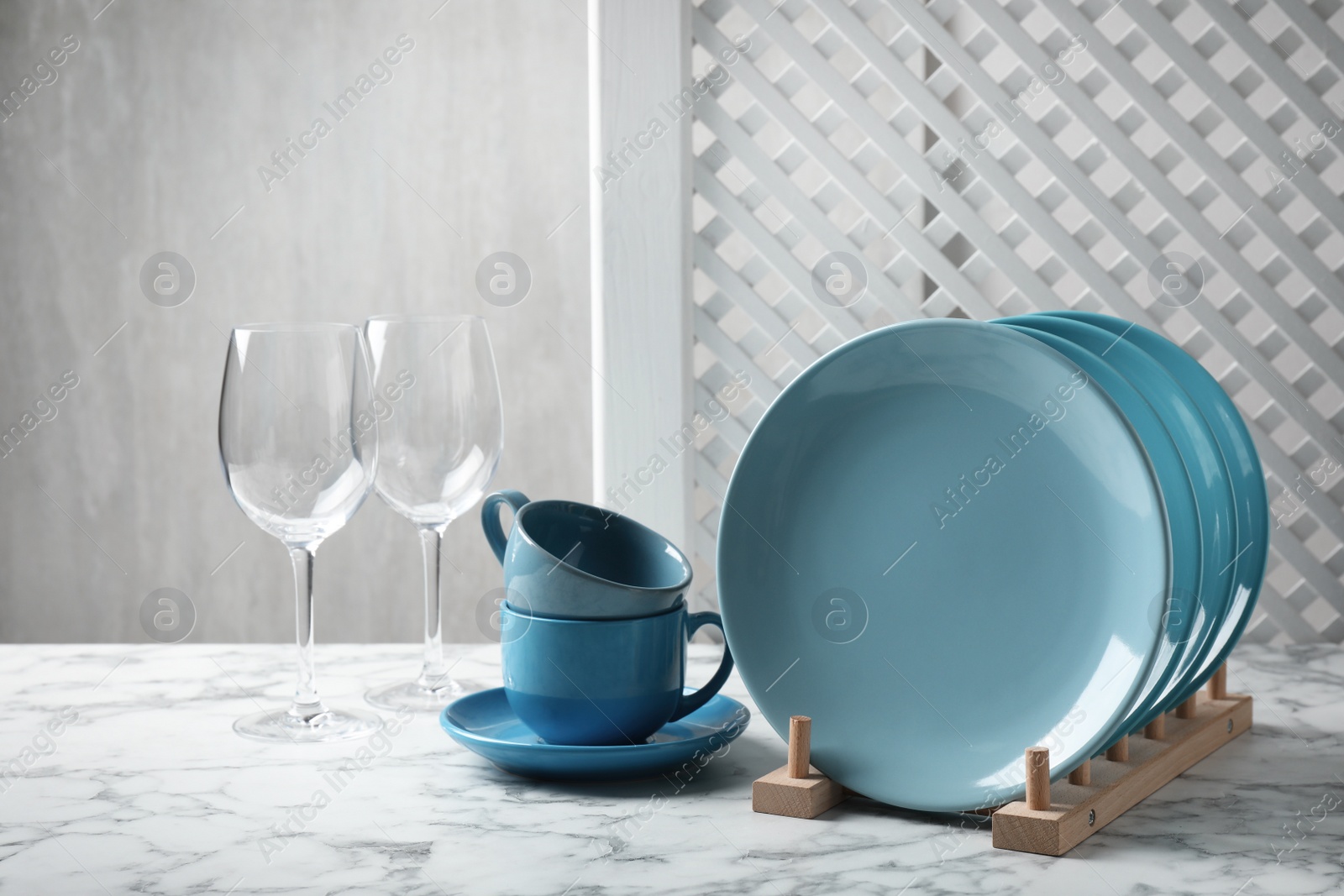 Photo of Set of clean dishware and glasses on white marble table