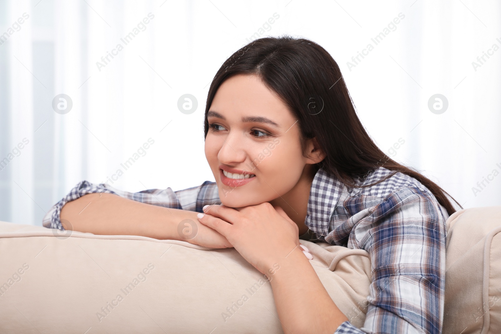 Photo of Young woman relaxing on couch at home