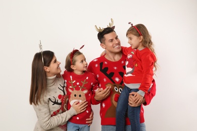 Photo of Family in Christmas sweaters and festive headbands on white background