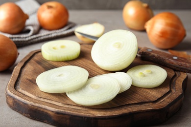 Photo of Wooden board with cut ripe onion on table, closeup