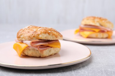 Photo of Delicious bagel with ham and cheese on light grey table. Space for text
