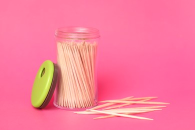 Photo of Wooden toothpicks and holder on pink background. Space for text