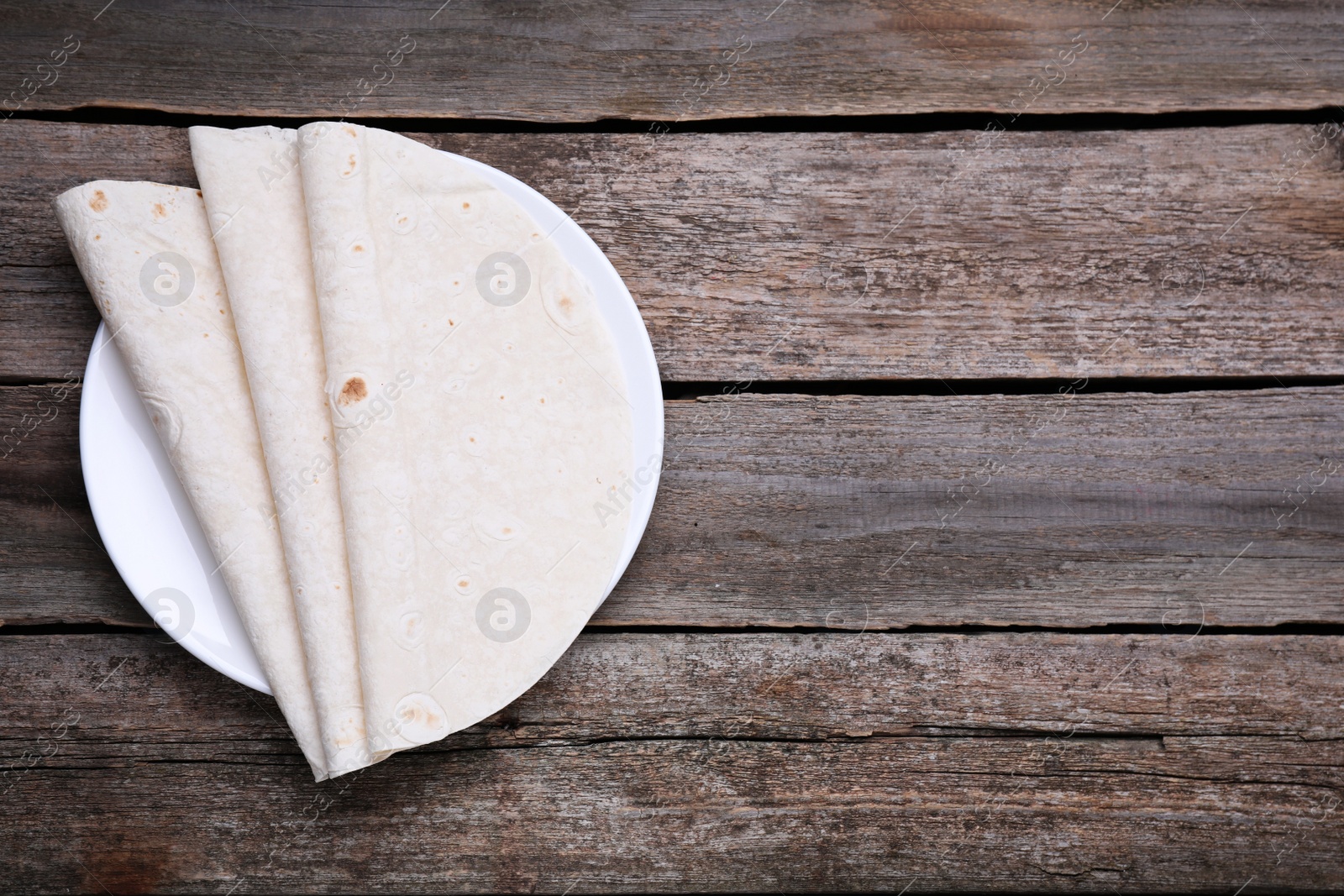 Photo of Delicious folded Armenian lavash on wooden table, top view. Space for text