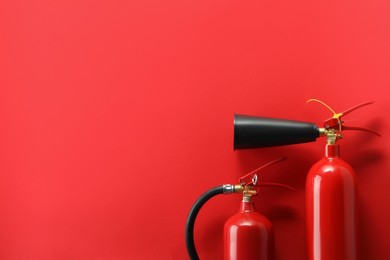 Photo of Fire extinguishers on red background, flat lay. Space for text