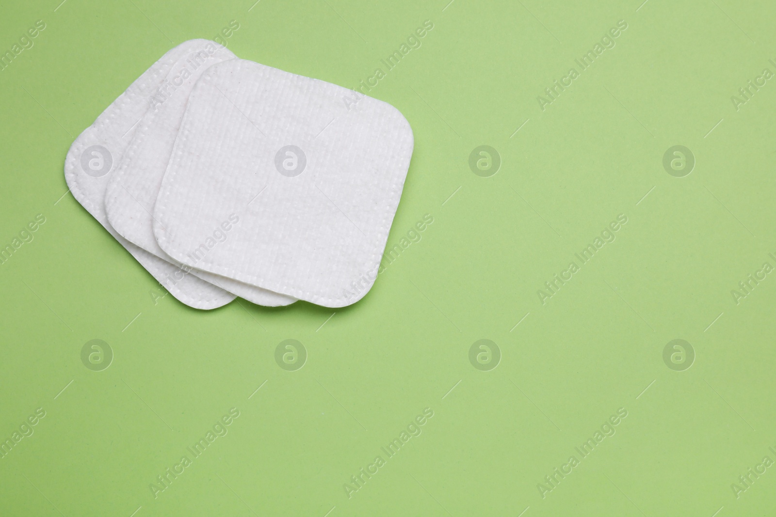 Photo of Cotton pads on green background, flat lay. Space for text