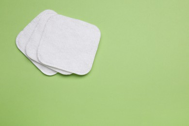 Cotton pads on green background, flat lay. Space for text