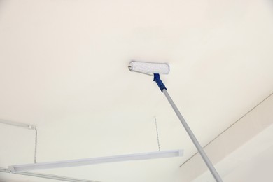 Painting ceiling with white dye indoors, low angle view