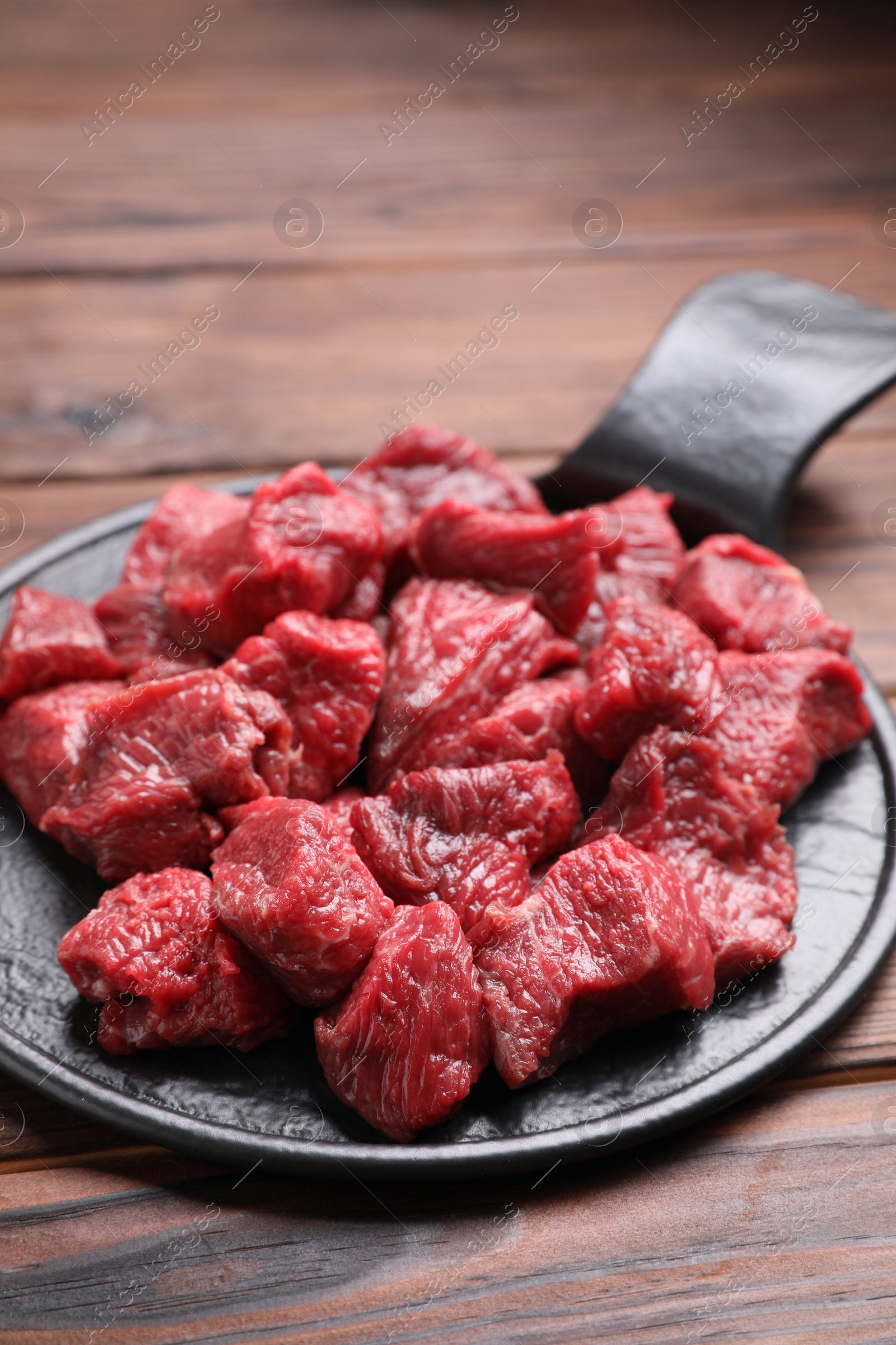 Photo of Pieces of raw beef meat on wooden table, closeup