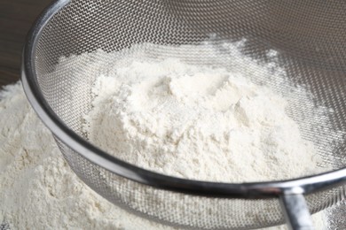 Photo of Metal sieve with flour on table, closeup