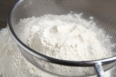 Metal sieve with flour on table, closeup