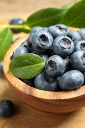 Bowl of tasty fresh blueberries on wooden table, closeup