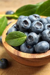 Photo of Bowl of tasty fresh blueberries on wooden table, closeup