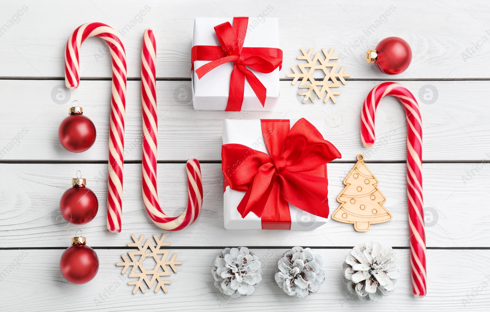 Photo of Flat lay composition with candy canes and Christmas decor on white wooden table