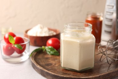 Photo of Pizza dough starter in glass jar, products and whisk on gray table