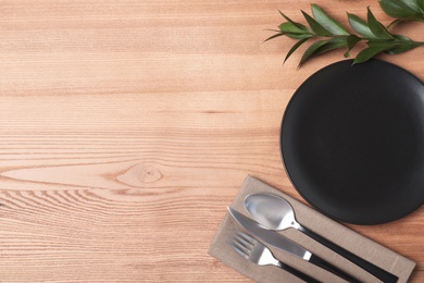 Photo of Flat lay composition with plate, cutlery and napkin on wooden background. Space for text