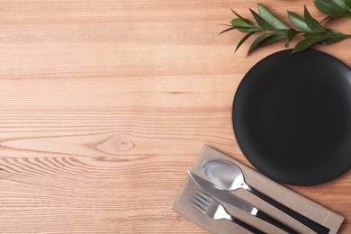 Flat lay composition with plate, cutlery and napkin on wooden background. Space for text